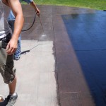 A man is spraying water on the side of a pool.