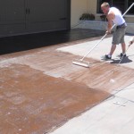 A man is cleaning the driveway with a mop.