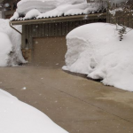 A driveway with snow piled on top of it.