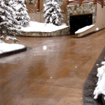 A driveway with snow on the ground and trees.