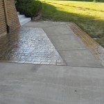 A brick walkway with a sidewalk and concrete steps.