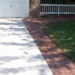 A driveway with brick and concrete curb and lawn.