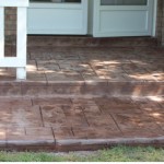 A porch with steps and a brick pattern.