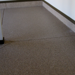 A floor with a brown speckled surface and black trim.