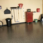 A garage with a red tool chest and a black trash can.