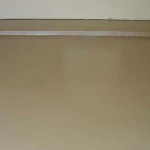 A tan floor with white trim and a light brown wall.