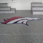 A large broncos logo is painted on the floor of this garage.