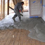 A man in grey work clothes is using a saw.