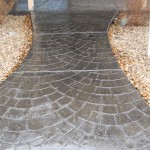 A walkway with a brick pattern and gravel.