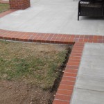 A patio with brick border and grass in the middle.