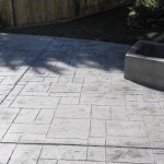 A cement patio with a fire pit in the middle of it.