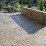 A patio with a bench and wall in the background.