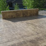 A patio with a bench and trees in the background.