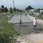 A group of people standing around a cement driveway.