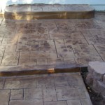 A patio with steps and a stone wall.