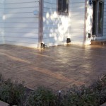 A patio with a brick floor and a flower bed.