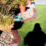 A person is standing in the grass near some rocks.