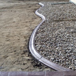 A concrete curb is shown with gravel on the ground.