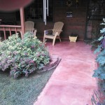 A patio with chairs and plants in the yard.