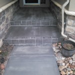 A cement walkway with steps leading to the front door.