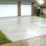 A driveway with two white doors and grass around it.