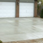 A driveway with two white doors and concrete.