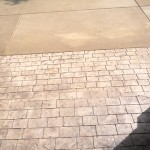 A sidewalk with brick and concrete patterns on it.