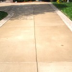 A sidewalk with grass growing between the two sides.