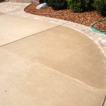 A sidewalk with a cement curb and a garden hose.