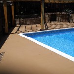 A pool with a blue water and a wooden deck