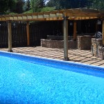 A pool with an outdoor grill and seating area.