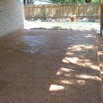 A patio with a brick wall and a tree.