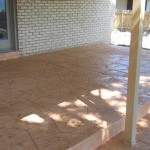 A patio with a brick wall and a wooden deck.