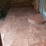 A patio with a door and steps leading to the front of it.