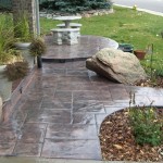 A patio with a stone bench and a rock.