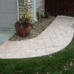 A walkway with grass and rocks in the front yard.