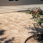 A patio with a flower bed and brick pavers.