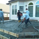 A group of men working on the ground in front of a house.