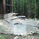 A patio area with rocks and trees in the background.