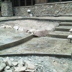 A stone patio with steps and rocks around it.