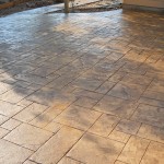 A patio with a brick pattern and a concrete floor.