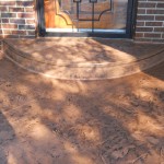 A brick patio with a door and steps leading to the front of it.