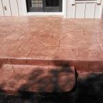 A cement patio with steps leading to the front door.