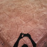 A person 's shadow on the ground of a brick floor.