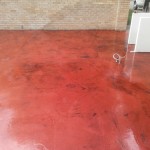 A red floor with black spots and a white wall