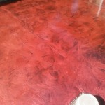 A red floor with some brown and black spots