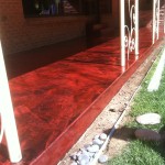 A red walkway with white posts and concrete