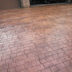 A brick driveway with a garage door in the background.