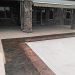 A pool with a stone wall and concrete floor.