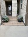 A porch with plants and steps leading to the house.